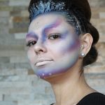 Female model with up-do hairstyle, glitter accents and tight cornrow braids on sides with alien makeup on her face