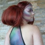 Female model with red hair puffed out with small braid details in alien makeup on her face and back