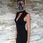 Body shot of female model with up-do hairstyle wearing black dress and in alien makeup that includes a zipper opening down her face